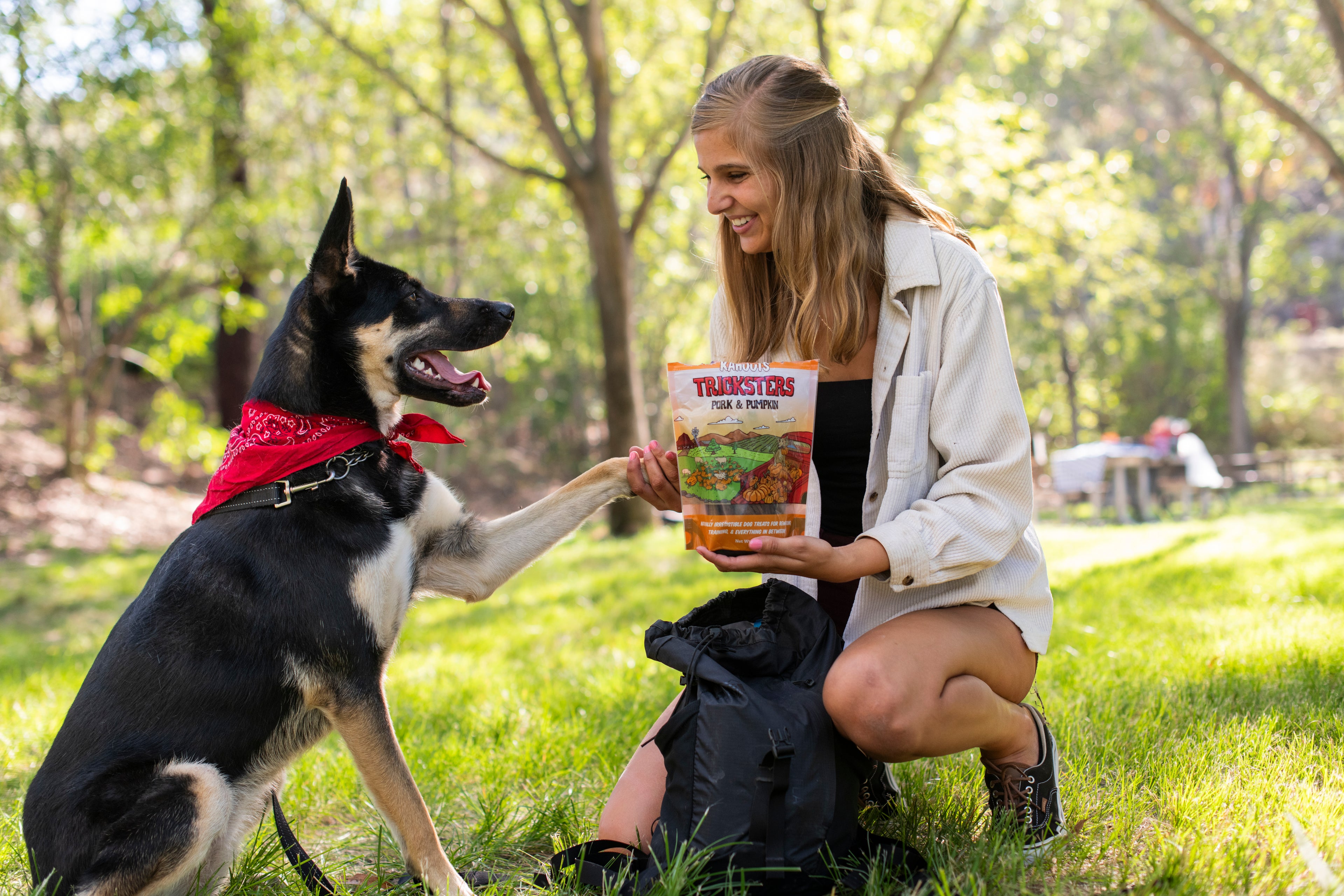 Woman in a park with a dog, holding a bag of treats.