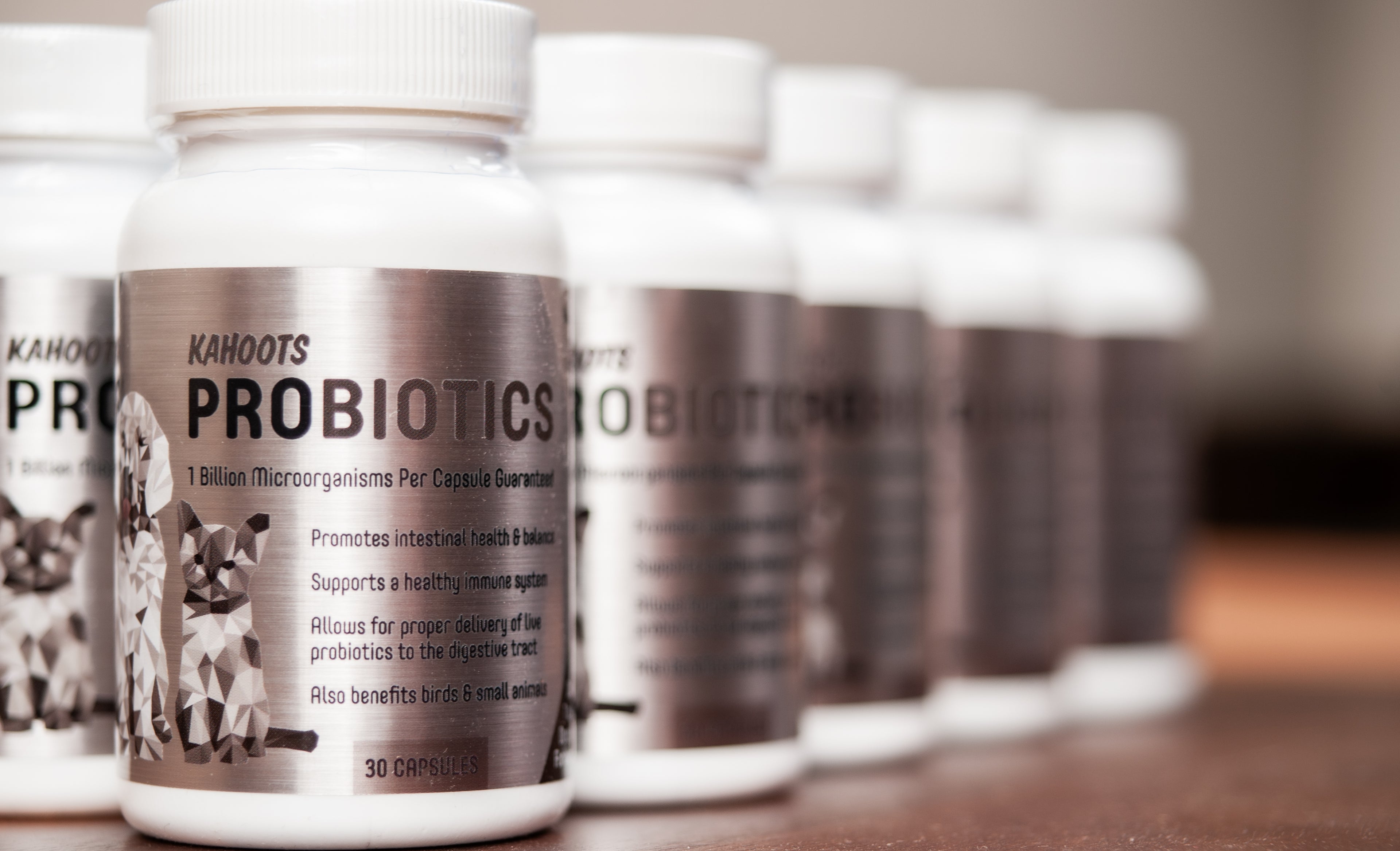 Row of Kahoots Probiotics bottles on a wooden surface with a blurred background