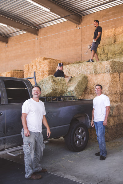 Mike and Ethan standing in front of a truck as hay is loaded in the bed