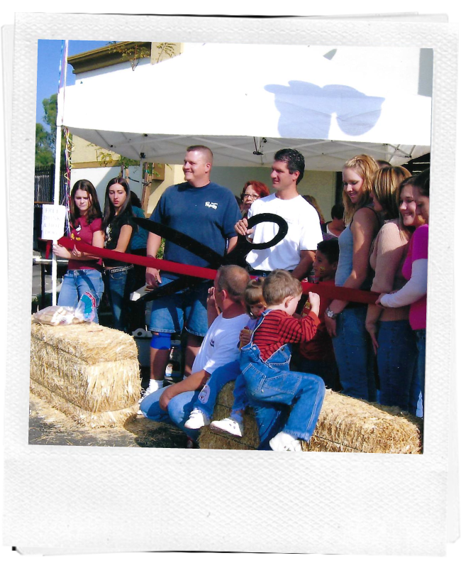 Mike, Ethan, family and friends cutting a ribbon.
