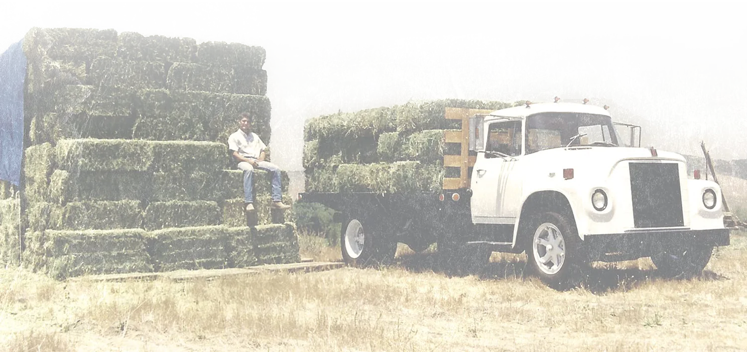 Mike sitting on a hay stack next to an old delivery truck
